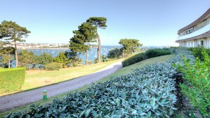 A coastal landscape with a pathway, trees, and a building with a curved roof overlooking the sea. - Lovely apartment for 2 people with WIFI, TV and terrace (La Richardais)