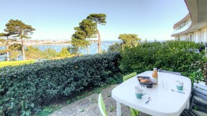 A balcony with a table set for two, overlooking a marina with boats and a clear view of the sea. - Lovely apartment for 2 people with WIFI, TV and terrace (La Richardais)