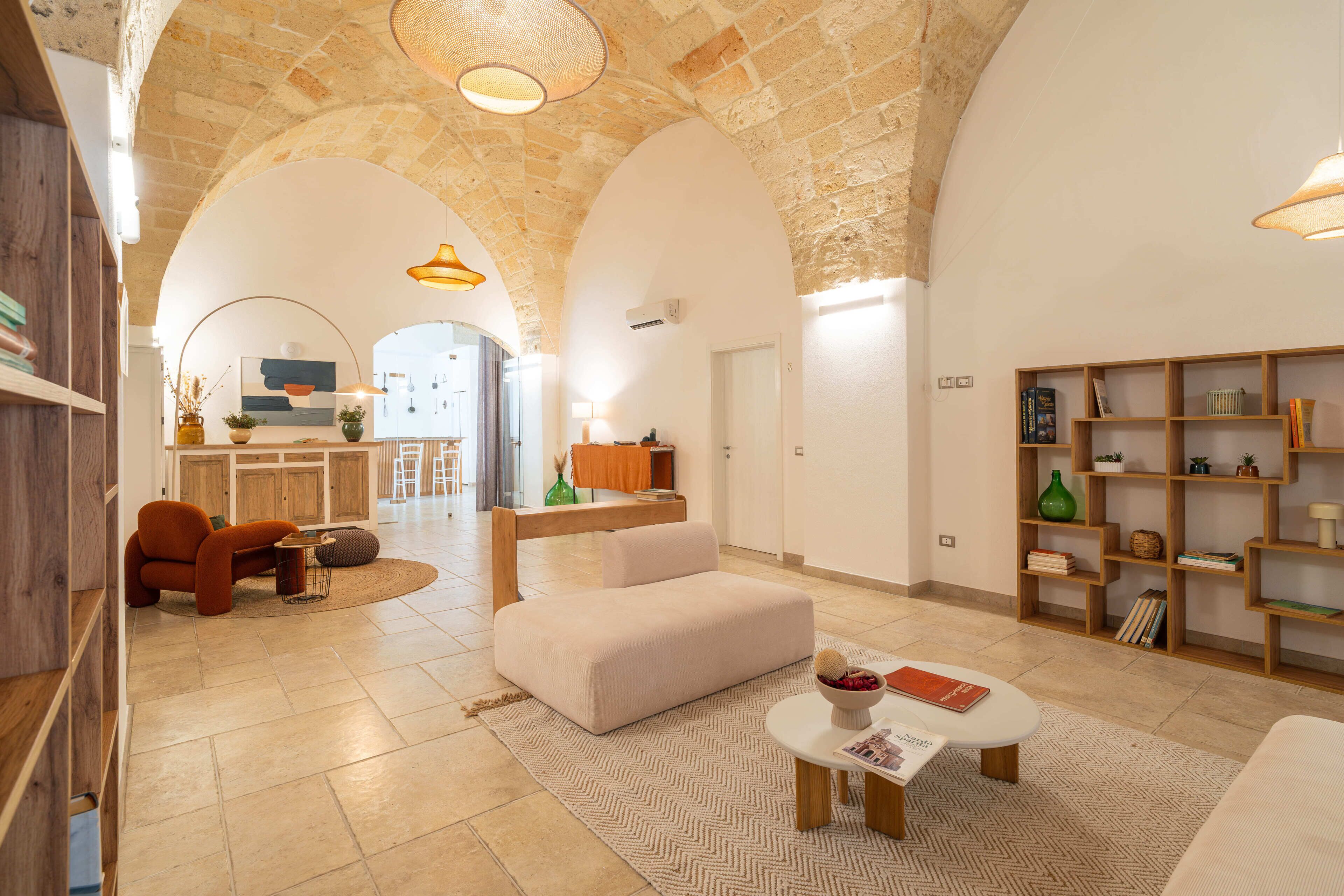 A spacious living area with a stone ceiling, a sofa, a coffee table, and a bookshelf.