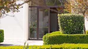 A modern building with a glass entrance, surrounded by well-maintained hedges and a tree. - Mediterranea Residence (Nardò)