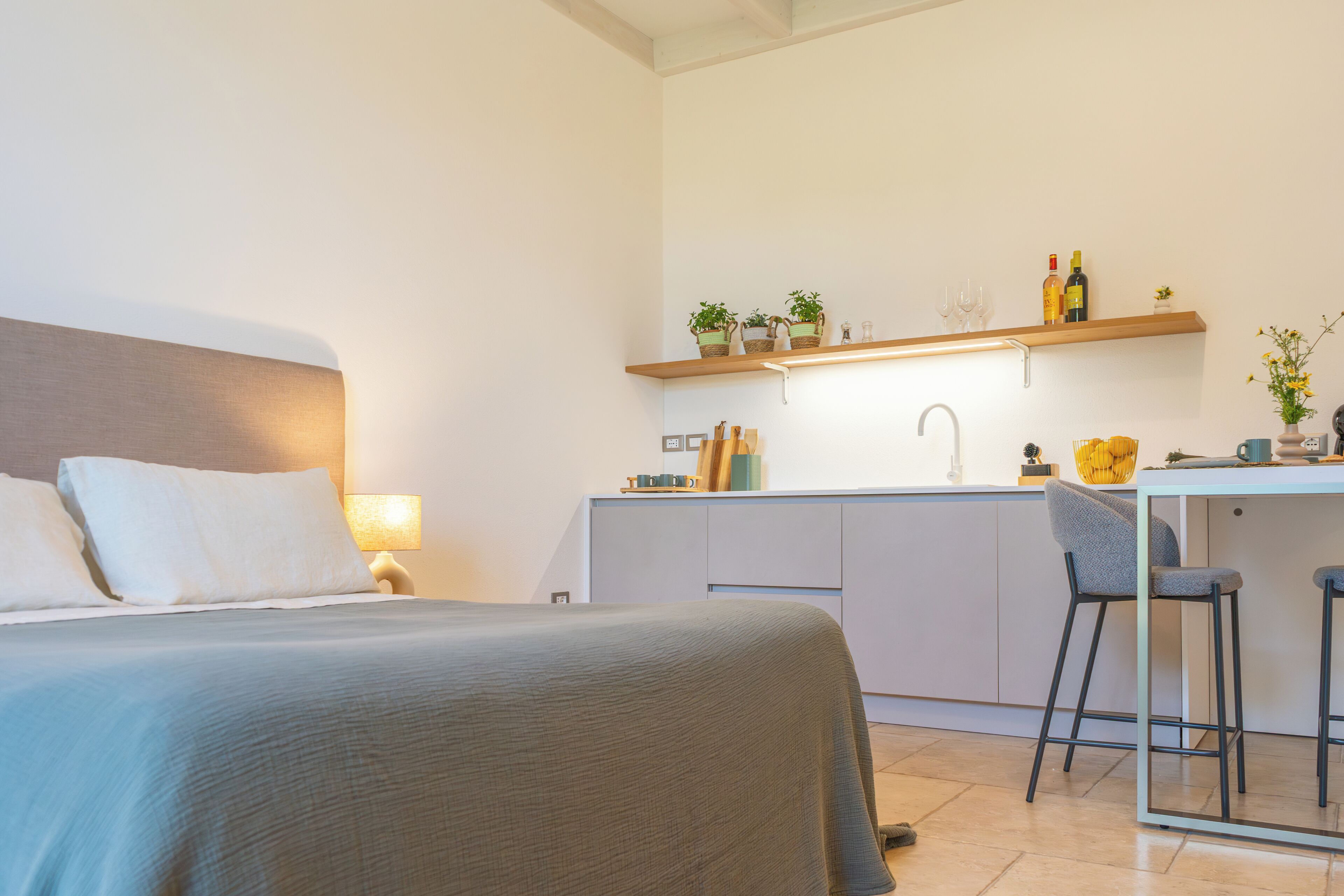 Ein kompaktes Hotelzimmer mit Bett, einer kleinen Küchenzeile, einer Bar und einem Esstisch.
