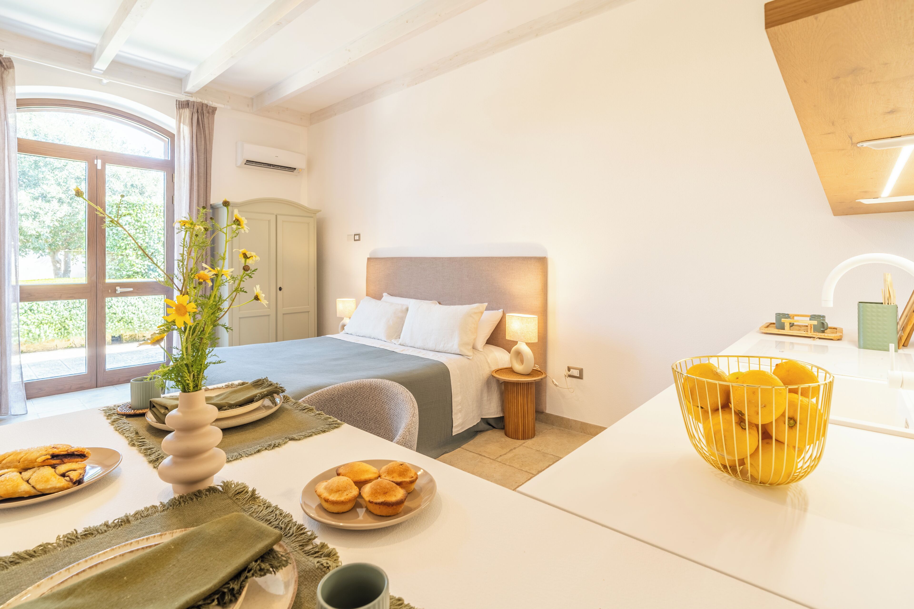 A hotel room with a bed, bedside table, lamp, and a window with curtains.