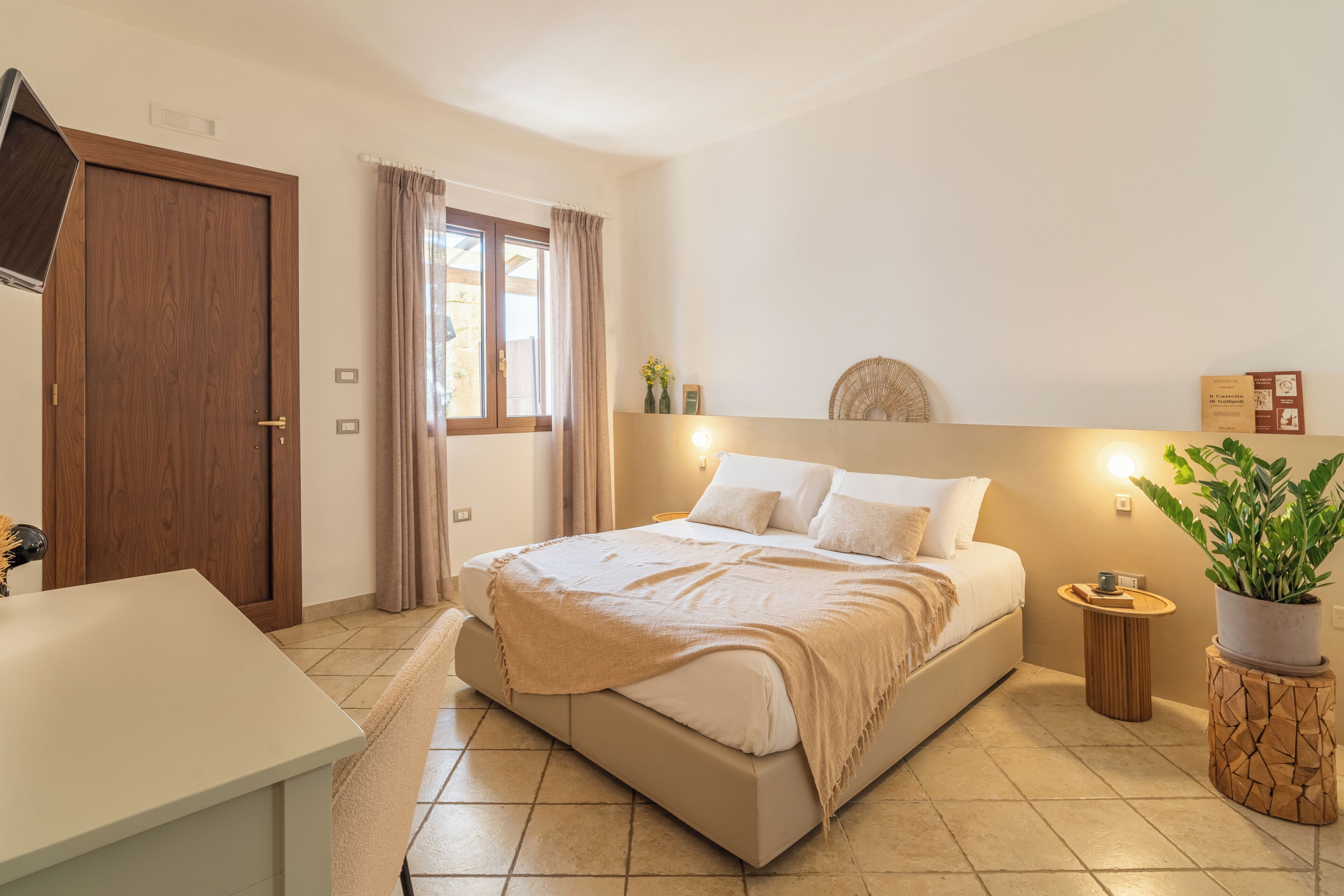 A bedroom with a bed, bedside table, and a potted plant.