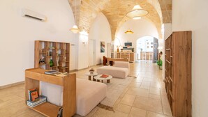 A spacious interior with a high arched ceiling, a wooden bookshelf, a seating area, and a view into another room. - Mediterranea Residence (Nardò)