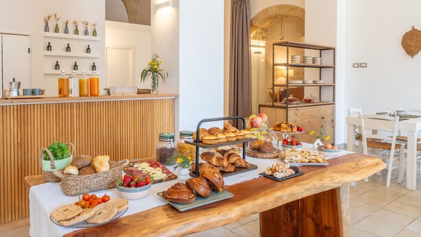 A breakfast buffet with a variety of foods, a wooden table, and a rustic interior with stone arches. - Mediterranea Residence (Nardò)