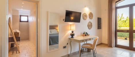 Habitación de hotel con cama, escritorio, silla, televisor y un amplio ventanal.