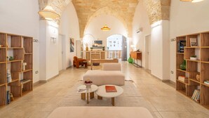 A spacious interior with a high arched stone ceiling, a central seating area, and wooden bookshelves on either side. - Mediterranea Residence (Nardò)