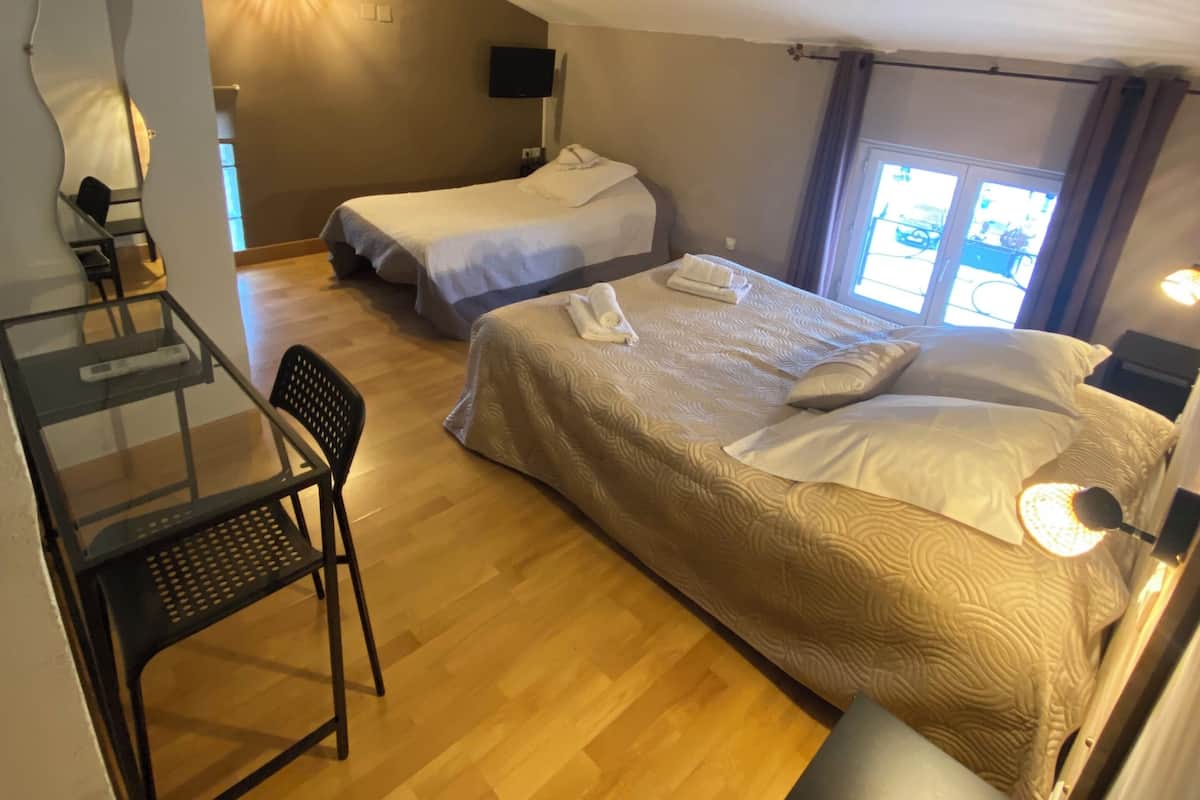 A room with two beds, a desk, and a chair.
