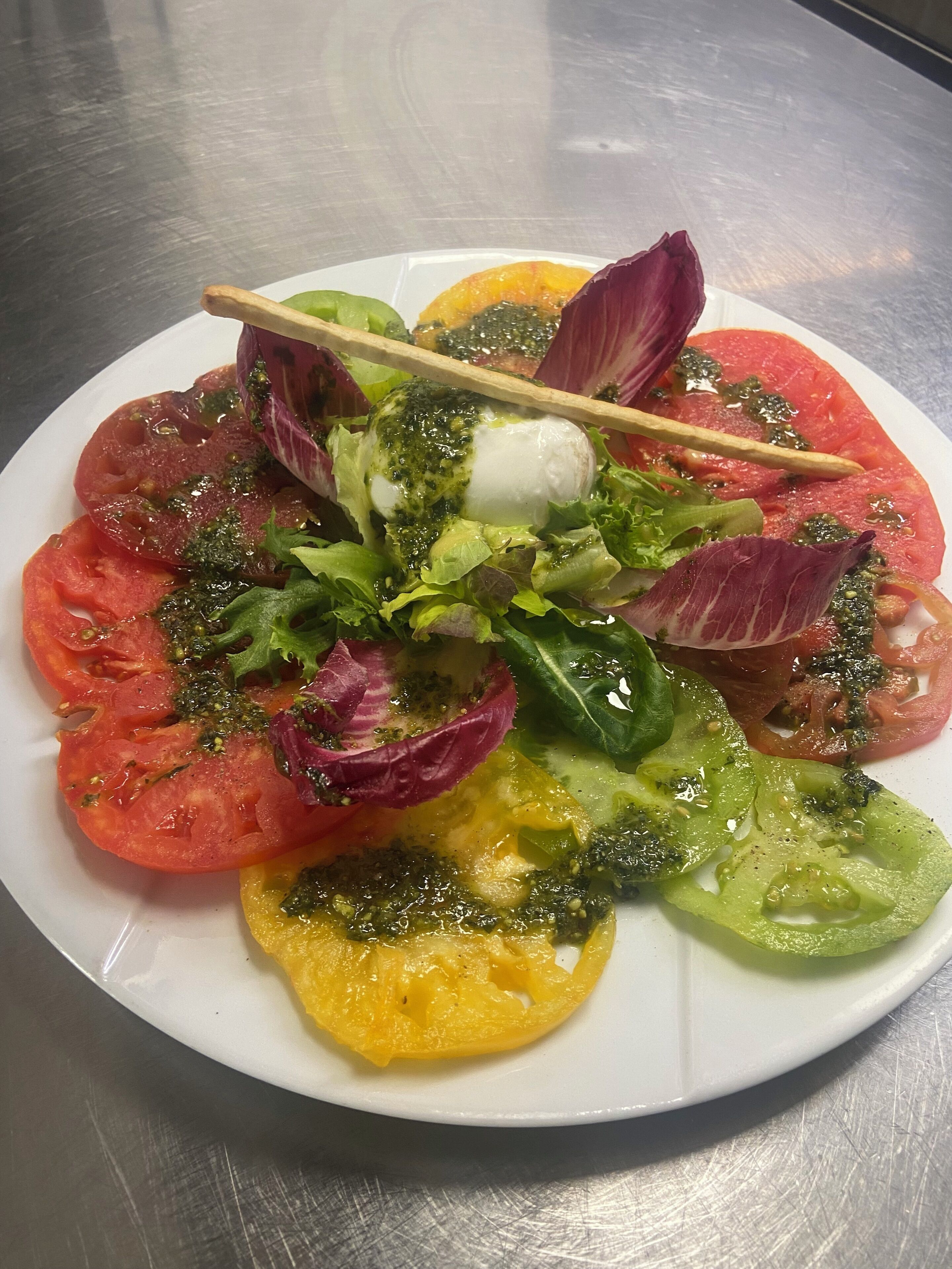 A plate of fresh salad with various vegetables and a dollop of cream.