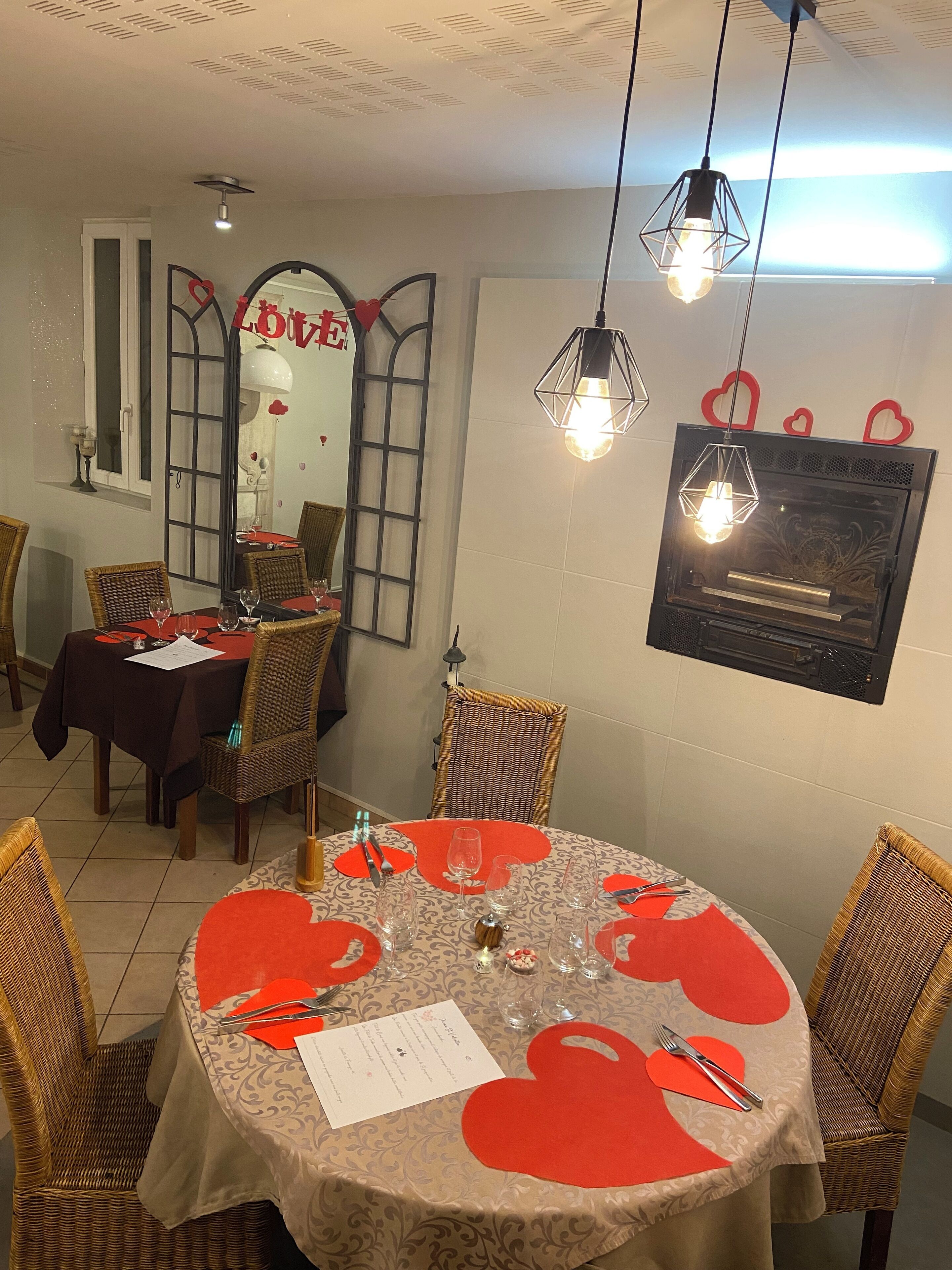 Un área de comedor con mesas redondas, sillas de mimbre y decoraciones con forma de corazón.