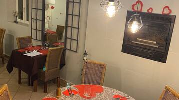 Un área de comedor con mesas redondas, sillas de mimbre y decoraciones con forma de corazón.