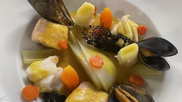 Un plat de fruits de mer composé de moules, de carottes et de pommes de terre, servi dans une assiette blanche.