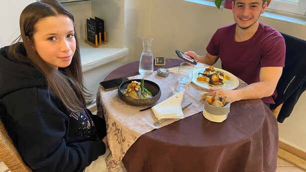 Two people dining at a table with a brown tablecloth, a glass of water, and a menu stand. - Hotel Restaurant l'Escapade (Bedoin)