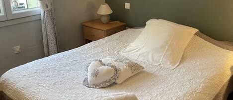 A neatly made bed with a patterned bedspread, two decorative pillows, and a folded towel.