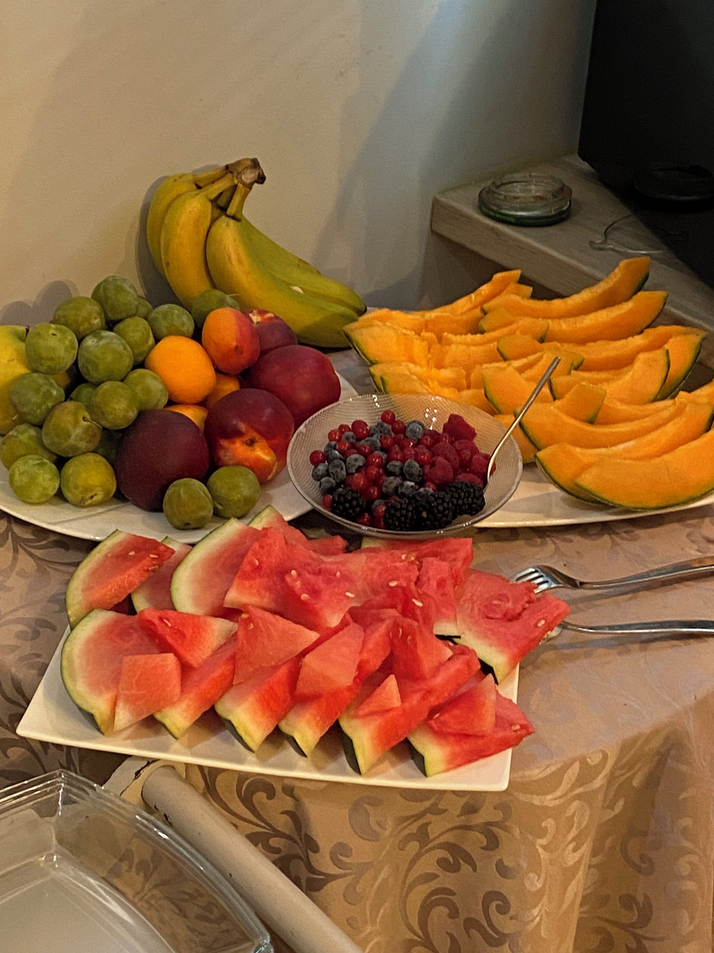 A fruit platter with various fruits including bananas, grapes, peaches, watermelon, and berries.