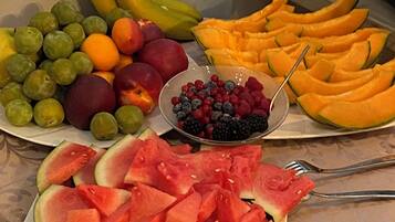 Una bandeja de frutas con diversas frutas como plátanos, uvas, melocotones, sandía y bayas.