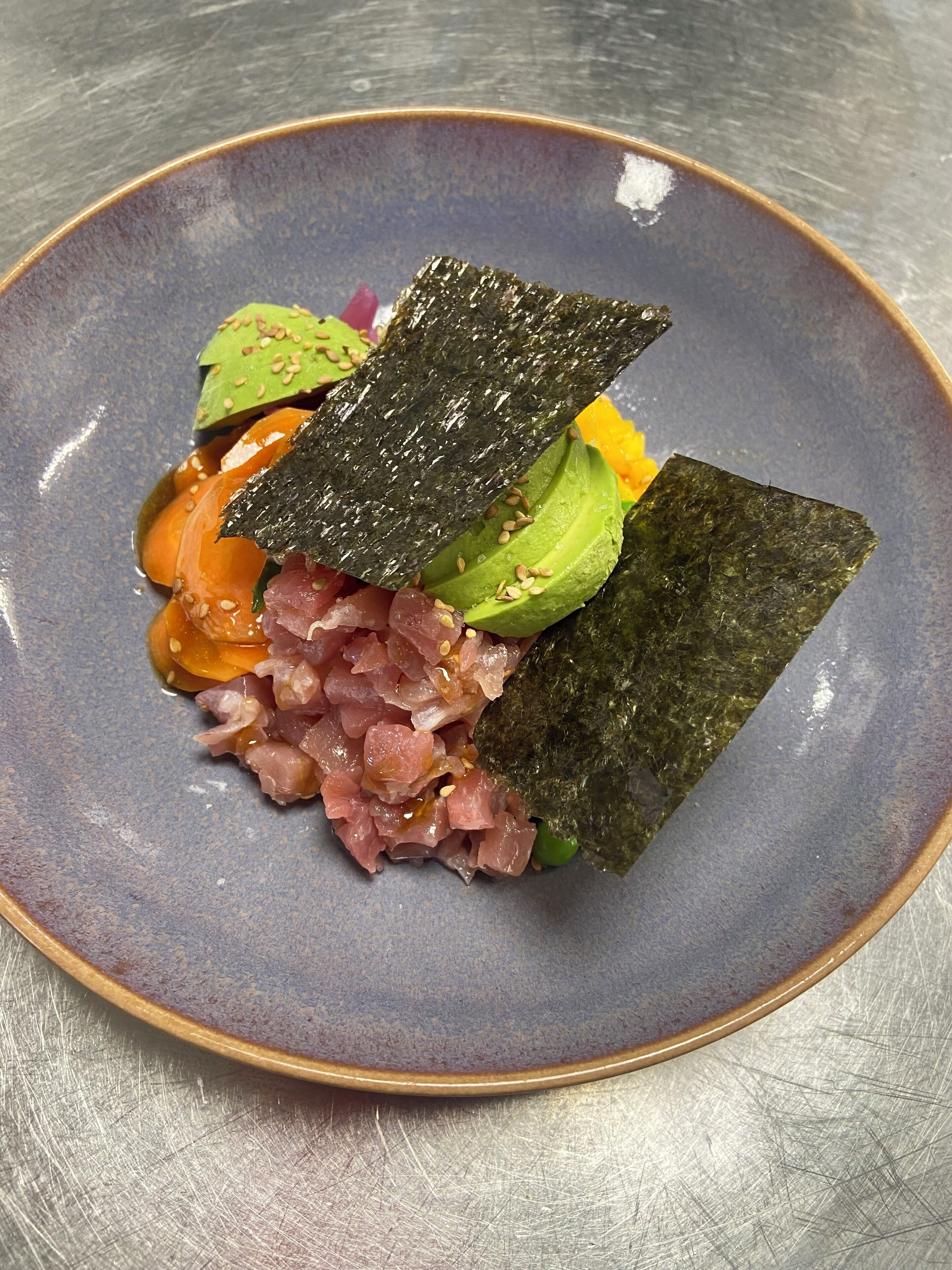 Un plato de sushi, aguacate y salsa.