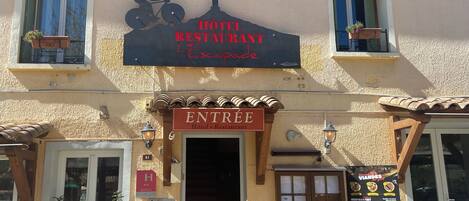 A hotel entrance with a sign reading "Hôtel Restaurant L'Escapade" and a bicycle silhouette.