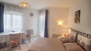 Un dormitorio con cama, escritorio, silla, un reloj de pared y un cuadro.