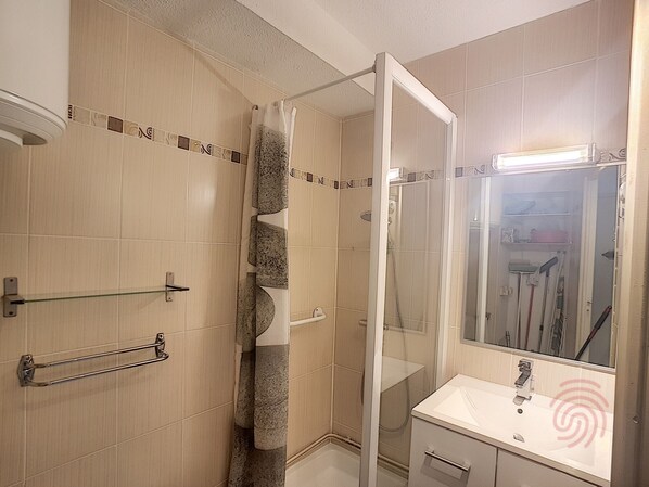 A bathroom with a glass shower enclosure, a sink with a mirror, and a towel rack. - Cozy 24m² Apt, Renovated, Balcony, 650m from Lamalou Thermal Baths, Pets Welcome (Lamalou-les-Bains)