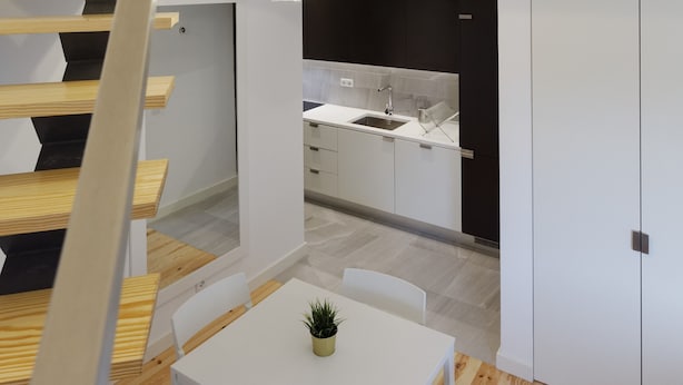 Cozinha moderna com bancada branca, armários pretos e pia de aço inoxidável.