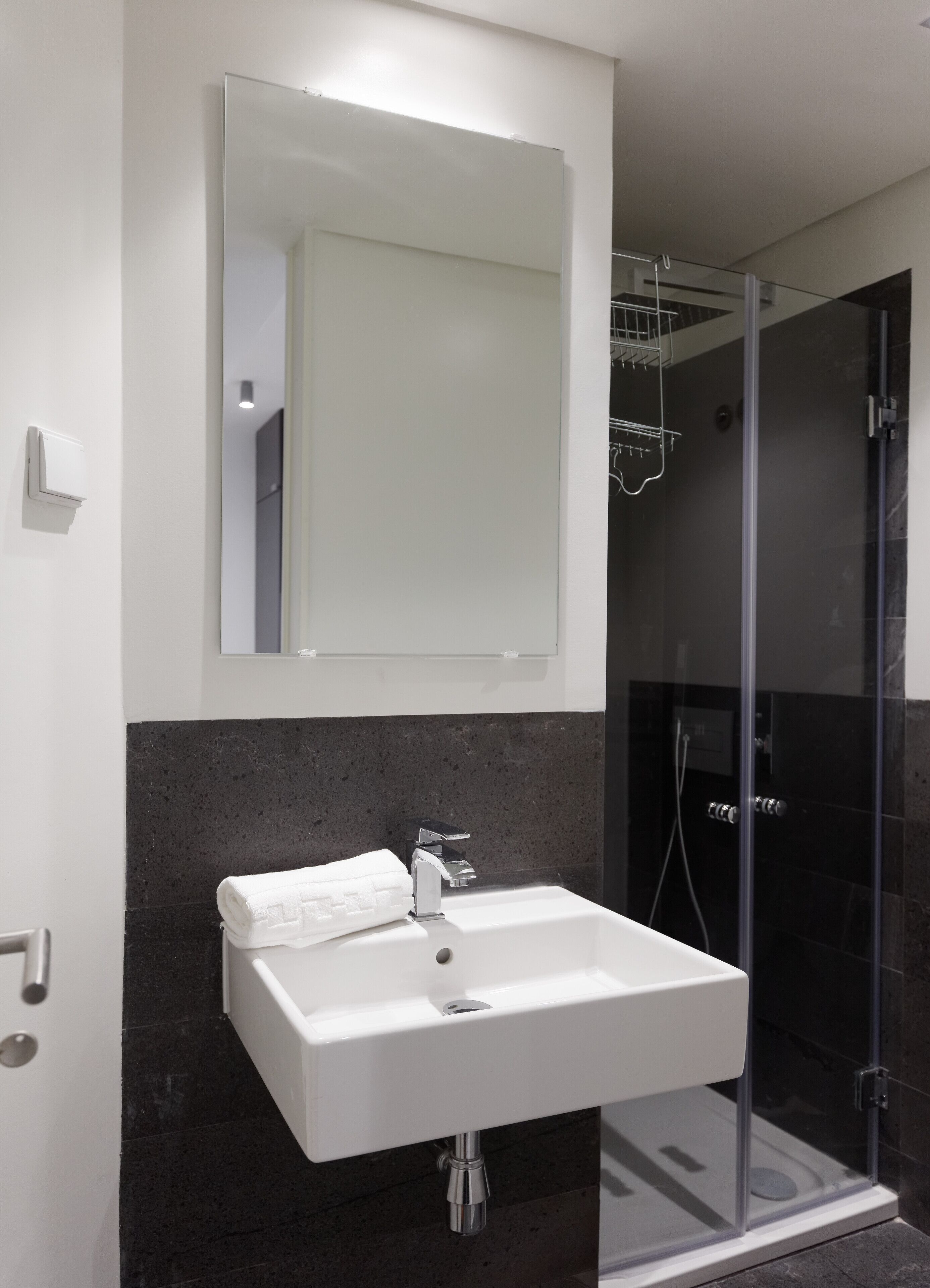 A modern bathroom with a white sink, a large mirror, and a glass-enclosed shower.