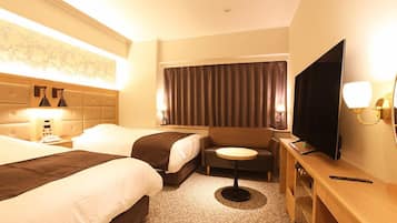 A hotel room with two beds, a sofa, a small round table, a TV, and a desk.