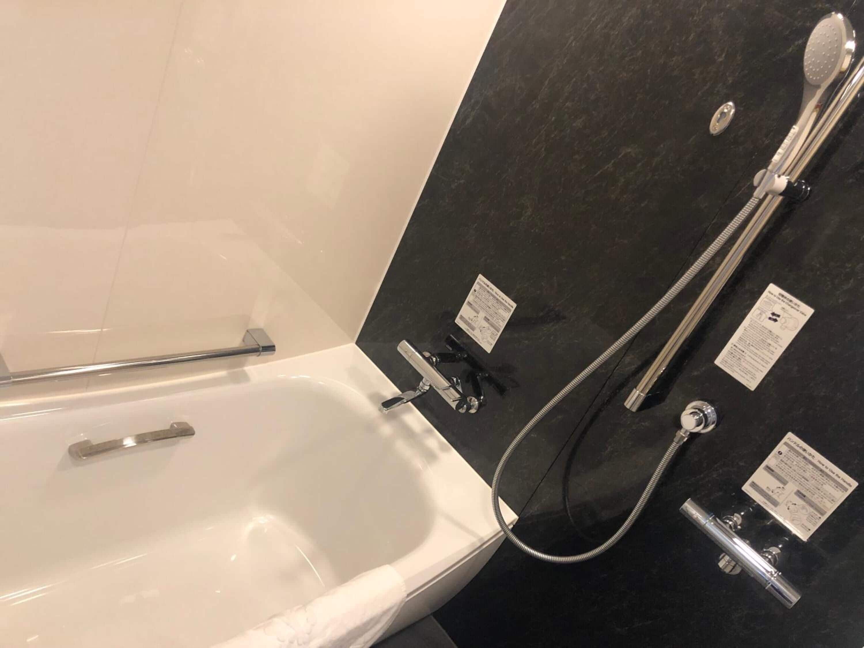 A bathroom with a bathtub, a shower, and a hand shower.