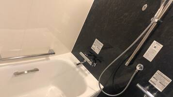 A bathroom with a bathtub, a shower, and a hand shower.