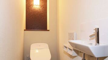 A small, narrow bathroom with a white toilet, a wall-mounted sink, and a light fixture above the toilet.