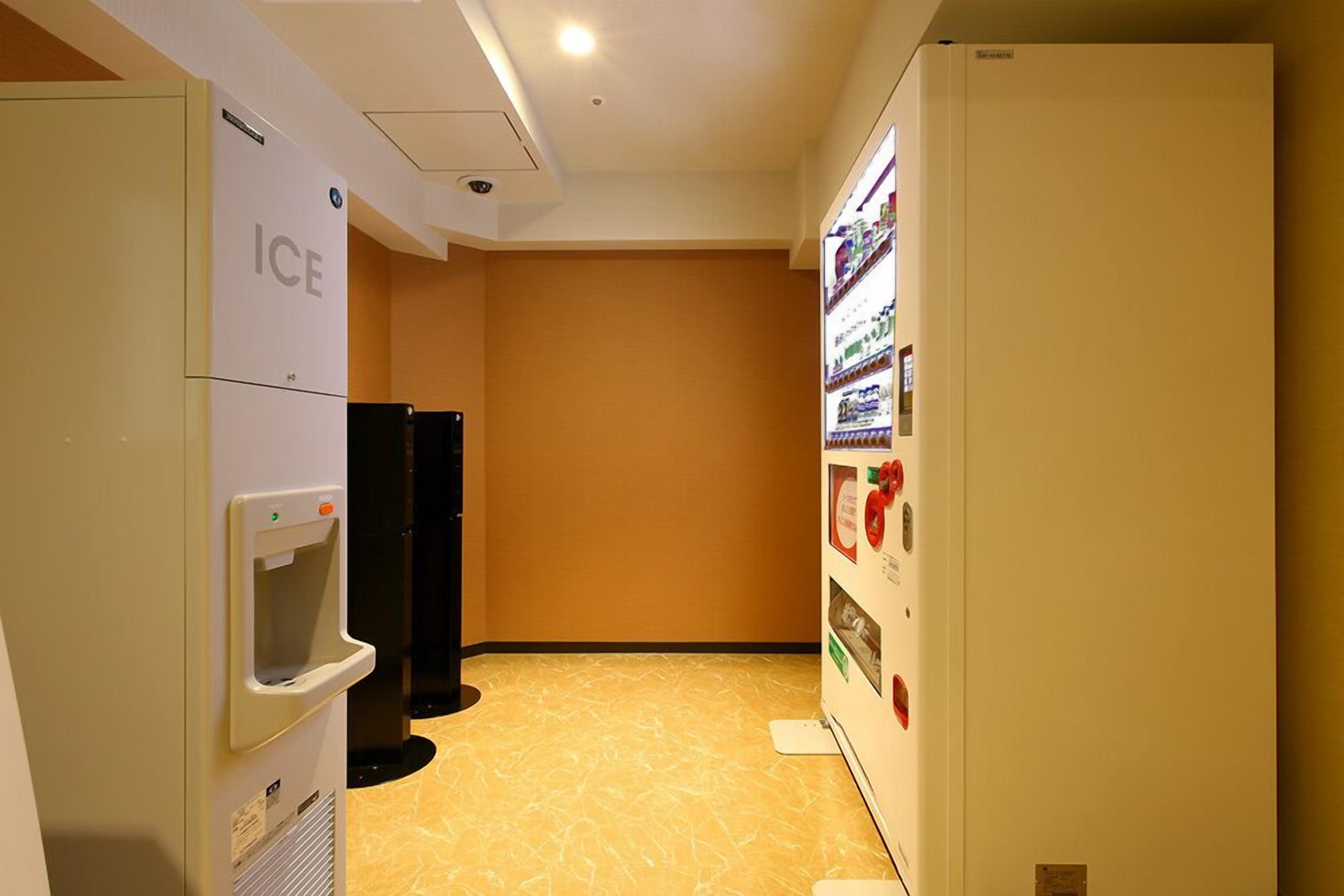A hallway with an ice dispenser, a refrigerator, and a vending machine.