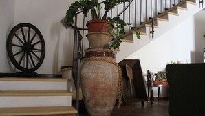 A staircase with a large vase and a wooden wheel decoration. - B&B Le Macine 1868 (Paceco)