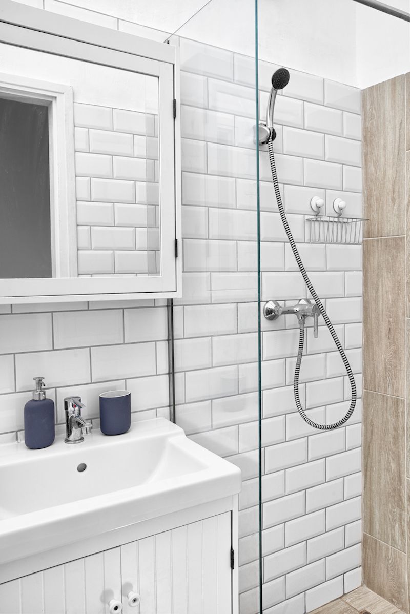 A bathroom with a white sink, a mirror, and a shower with a glass door.