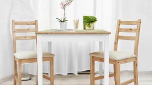 A small, white-framed table with two wooden chairs, a potted plant, and a green decorative item on the table. - Elegant Ernesto (Budapest)