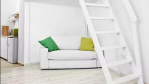 A white staircase leading to a loft area with a white sofa and pillows. - Elegant Ernesto (Budapest)