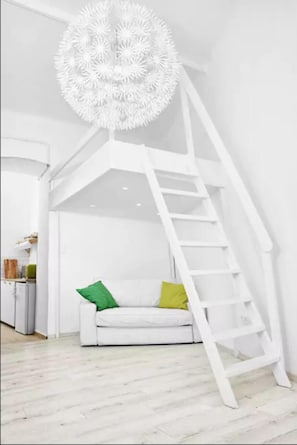 Staircase leads to an upper level, featuring a minimalist design with a white sofa and abstract light fixture.