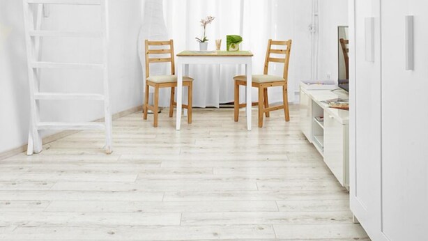 A bright, white room with a wooden floor, a white table with chairs, a white bookshelf, and a white cabinet. - Elegant Ernesto (Budapest)