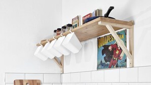 A kitchen with a green toaster, a wooden cutting board, a sink, and a wall-mounted shelf with kitchen items. - Elegant Ernesto (Budapest)