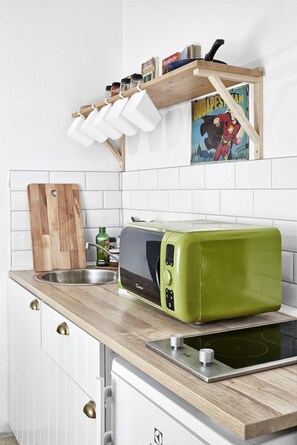 Enjoy cooking in this well-equipped kitchen with a toaster oven, stainless steel sink, and wooden cutting board.