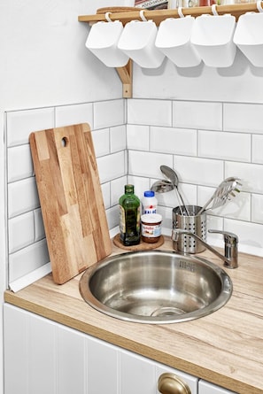 Enjoy cooking in this well-equipped kitchen with a stainless steel sink, wooden countertop, and ample storage.