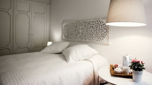 A bedroom with a bed, a bedside table with a lamp, a decorative wall piece, and a small potted plant. - B&B Barberia (Treviso)