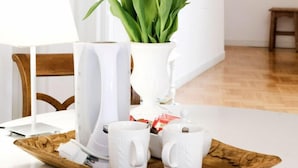 A dining area with a white table, a white vase with orange tulips, and white cups on a wooden tray. - B&B Barberia (Treviso)