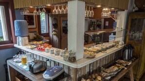 A buffet setup with various food items, a coffee machine, and a wine glass rack. - Pousada Casa da Lagoa (Florianópolis)