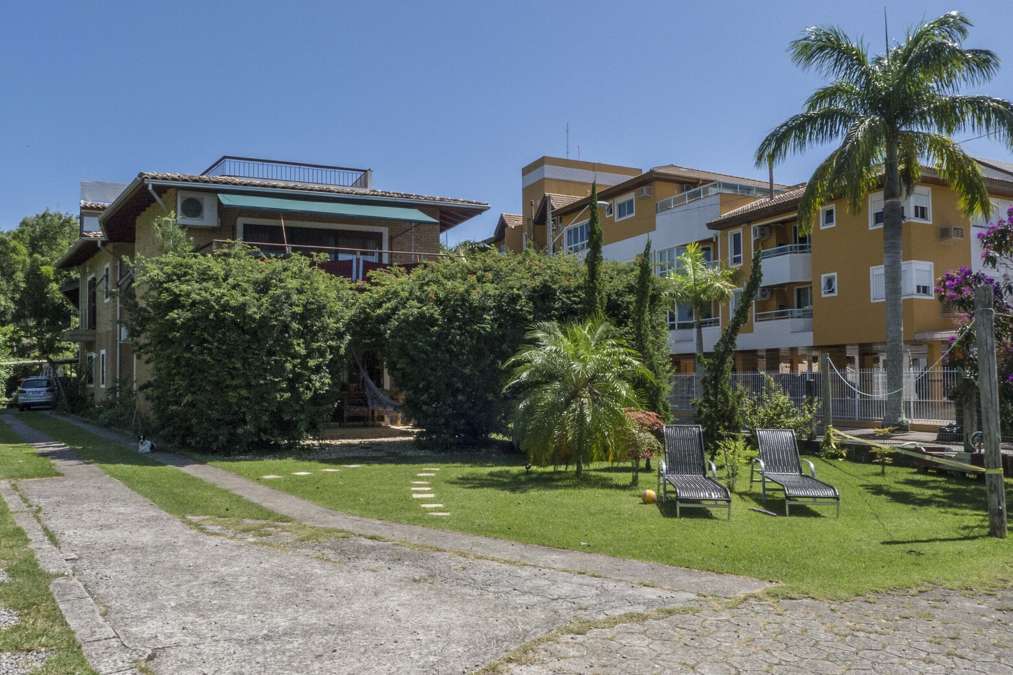 A residential building with a paved pathway, a small lawn area, and a few lounge chairs.