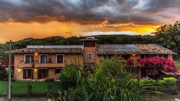 A two-story house with a brick facade, solar panels, and a balcony. - Pousada Casa da Lagoa (Florianópolis)