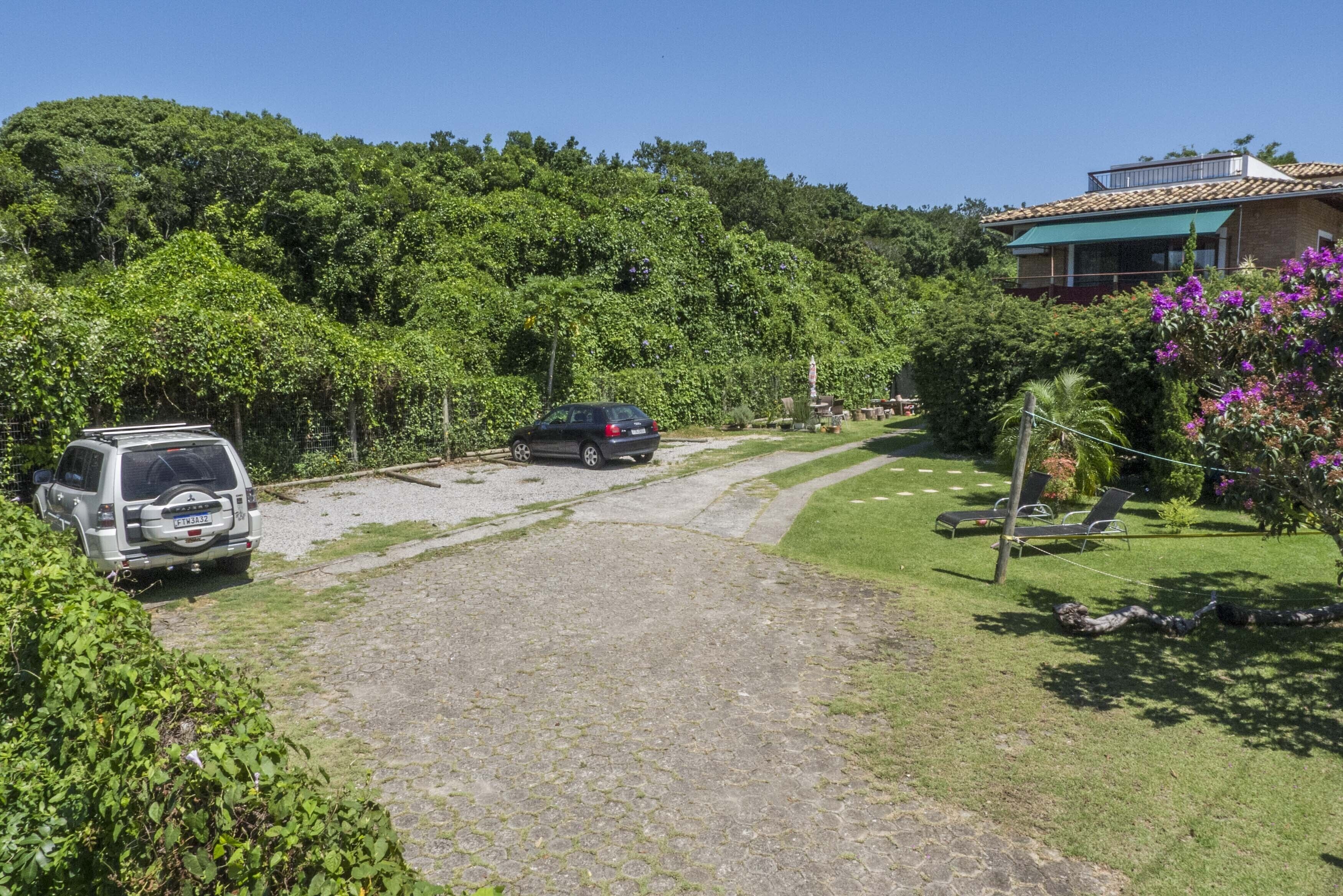 A paved driveway leading to a house with a car parked on the left.