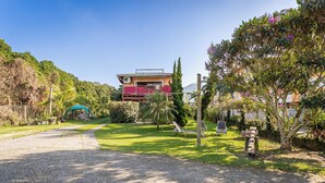 A residential property with a paved driveway, a grassy lawn, and a two-story building with a balcony. - Pousada Casa da Lagoa (Florianópolis)