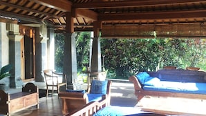 A covered outdoor seating area with wooden furniture and a thatched roof. - Puri Sangkih (Munduk)