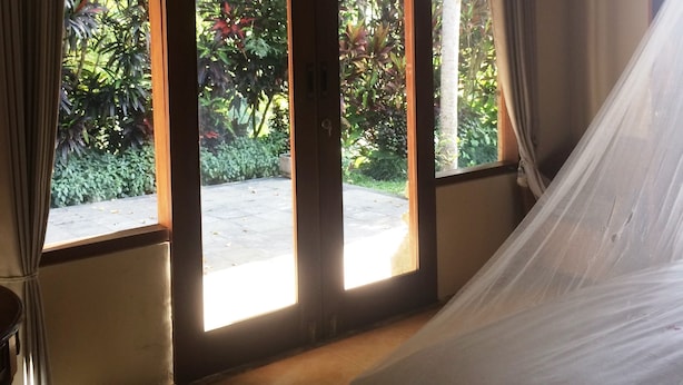 A room with a bed, large sliding glass doors, and a view of greenery outside. - Puri Sangkih (Munduk)