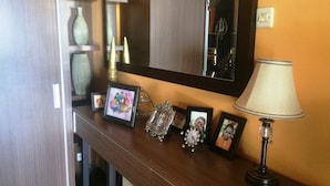 A wooden console table with a mirror above it, a lamp, and several framed pictures. - Puri Sangkih (Munduk)